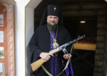 Archevêque Pitrim avec un fusil mitrailleur dans les mains